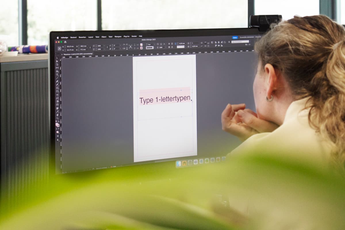 Persoon achter de computer kijken naar adobe fonts in Indesign